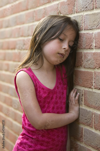 Shot of a sad young girl against a brick wall