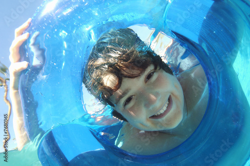 Boy looking through inflatable raft in swimming pool, underwater view