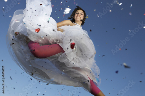 Photo: Portrait of young woman in wedding dress jumping Portrait of young woman in wedding dress jumping