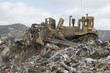 Digger moving waste at landfill site
