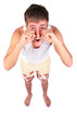 young man in shorts rubs  eyes