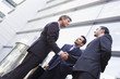 Group of businessmen shaking hands outside office