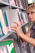 Photo: woman looking through books in library woman looking through books in library