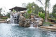 A pool with a waterfall in a luxury backyard A pool with a waterfall in a luxury backyard