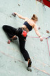 The climber young girl trains on an artificial rock
