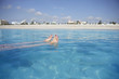 Photo: South Africa, Cape Town, woman floating in sea, low section, beach in background, surface level South Africa, Cape Town, woman floating in sea, low section, beach in background, surface level