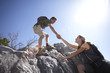Photo: Couple climbing rock in bright sunlight, man assisting woman, side view, low angle view Couple climbing rock in bright sunlight, man assisting woman, side view, low angle view