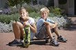 Photo: Boy (7-9) and girl (8-10) sitting on brick driveway, holding skateboards, smiling, portrait Boy (7-9) and girl (8-10) sitting on brick driveway, holding skateboards, smiling, portrait