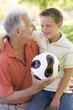 Grandfather and grandson outdoors with ball smiling