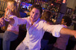 Young man in nightclub approaching camera with arms outstretched