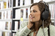 Photo: Young woman wearing headphones, listening to CDs in record shop, smiling, close-up, side view Young woman wearing headphones, listening to CDs in record shop, smiling, close-up, side view