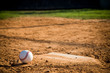 Baseball Sitting on a dirty homeplate.