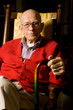 Senior Man Sitting with hands on Cane.
