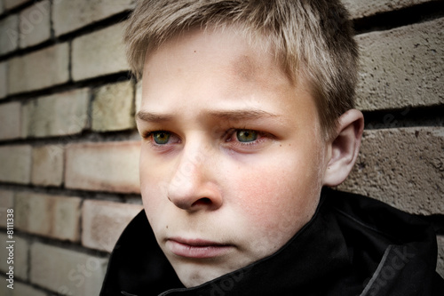 upset boy leaning against a wall