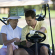 Couple in a golf buggy looking at a plan of the course and score card