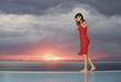 A woman walking along the edge of a pool at sunset