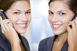 Two identical twin businesswomen using cellphones
