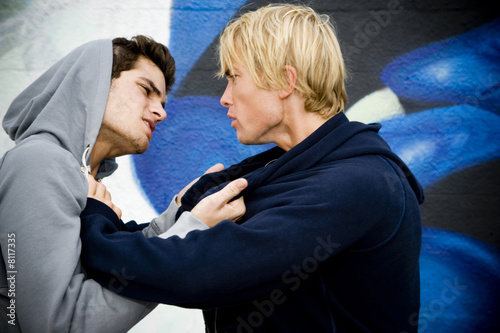 Photo: Two men fighting in front of a graffiti covered wall Two men fighting in front of a graffiti covered wall