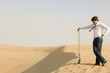 A young man standing in the desert with a spade