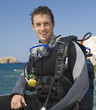 A male scuba diver sitting on a boat