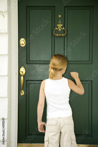 Photo: Little girl knocking at the front door of a house Little girl knocking at the front door of a house