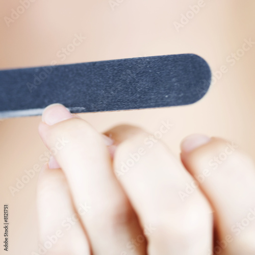 Foto: A young woman filing her nails A young woman filing her nails