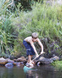 A young boy with a fishing net on a riverbank