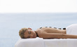 A young woman receiving a hot stone holistic treatment