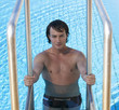 Portrait of a young man climbing into a swimming pool