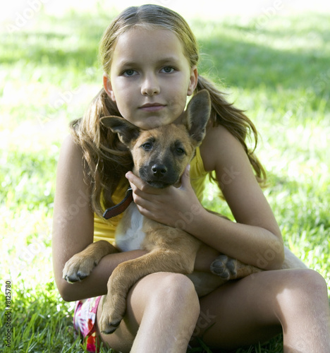 Photo: Young girl sitting in the garden holding a puppy Young girl sitting in the garden holding a puppy