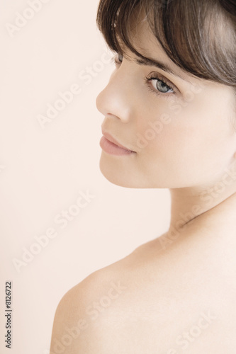 Foto: Portrait of young woman looking over her shoulder Portrait of young woman looking over her shoulder