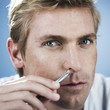 A young man using tweezers to pluck nasal hair