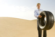 A man standing in the desert with a tyre