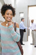 Photo: Woman holding house keys, smiling, portrait, male real estate agent shaking hands with man in background by stairs Woman holding house keys, smiling, portrait, male real estate agent shaking hands with man in background by stairs
