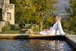 Photo: Senior woman wearing white bath robe, sitting outdoors by swimming pool, eyes closed, side view Senior woman wearing white bath robe, sitting outdoors by swimming pool, eyes closed, side view