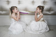 Two little girls wearing party dresses blowing party blowers