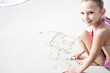 A young girl writing in the sand