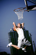 Foto: Young African American man jumping with a basketball on an urban basketball court Young African American man jumping with a basketball on an urban basketball court