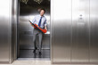 Young businessman holding fire extinguisher in lift