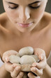 Young woman holding stones for heated stone therapy