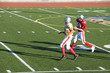 Photo: American football player chasing opposing receiver with ball during competitive game, side view American football player chasing opposing receiver with ball during competitive game, side view