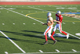 Photo: American football player chasing opposing receiver with ball during competitive game, side view American football player chasing opposing receiver with ball during competitive game, side view