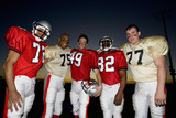 Photo: Five American football players standing side by side on pitch at sunset, smiling, front view, portrait Five American football players standing side by side on pitch at sunset, smiling, front view, portrait