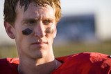 Photo: American football player wearing red football strip and black face paint, close-up, front view American football player wearing red football strip and black face paint, close-up, front view