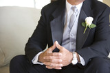 Photo: Senior groom, in formalwear, sitting on chair at wedding, thumbs pressed together, mid-section Senior groom, in formalwear, sitting on chair at wedding, thumbs pressed together, mid-section