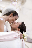 Photo: Bride and groom embracing and kissing outside church, profile, low angle view (tilt) Bride and groom embracing and kissing outside church, profile, low angle view (tilt)