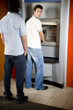 Young man using a cashpoint or ATM looking over his shoulder