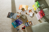 Photo: Mature woman sitting on floor at home, looking at colour charts, smiling, portrait, overhead view Mature woman sitting on floor at home, looking at colour charts, smiling, portrait, overhead view