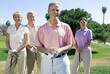 Photo: Two mature couples standing on golf course, playing golf, smiling, front view, portrait Two mature couples standing on golf course, playing golf, smiling, front view, portrait