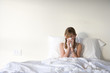 Photo: Girl (11-13) sitting upright in bed, blowing nose with handkerchief, front view Girl (11-13) sitting upright in bed, blowing nose with handkerchief, front view